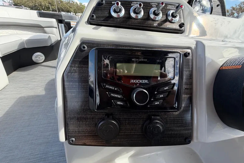 Slide: The Image of 2023 Lowe SS 210 boat dashboard with Kicker media center and control switches. - 23