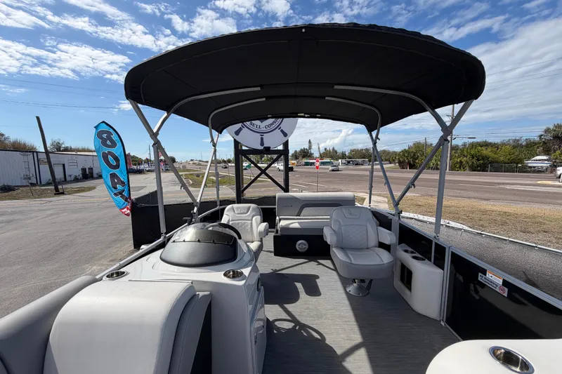 Slide: The Image of 2023 Lowe SS 210 pontoon boat with canopy, parked near a road under a blue sky. - 35