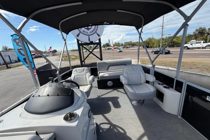 Slide: The Image of 2023 Lowe SS 210 pontoon boat interior with seating and helm, parked outdoors. - 37