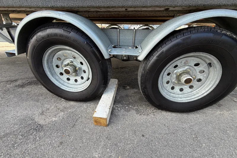 Slide: The Image of Trailer wheels of a 2023 Lowe SS 210, secured with a wooden block. - 50