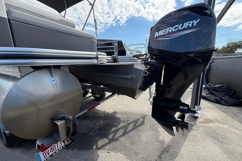 Slide: The Image of 2023 Lowe SS 210 pontoon boat with Mercury outboard motor, parked on a trailer. - 6