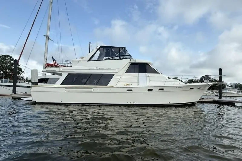 The Image of 1999 Bayliner 4788 Pilot House Motoryacht docked on calm water. - 0