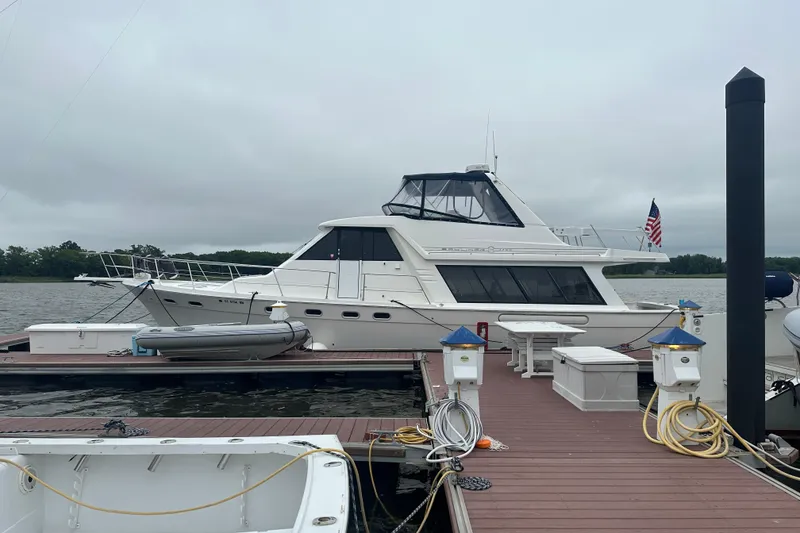 Slide: The Image of 1999 Bayliner 4788 Pilot House Motoryacht docked at marina with overcast sky. - 1