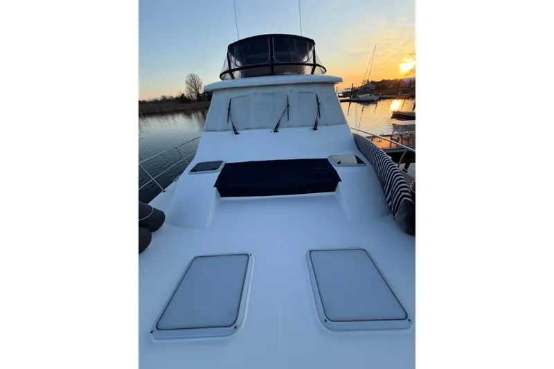 Slide: The Image of 1999 Bayliner 4788 Pilot House Motoryacht deck at sunset, docked by calm waters. - 12