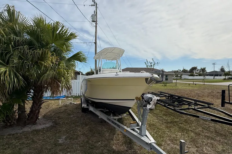 Slide: The Image of 2004 Rabalo 265 boat on trailer beside palm tree, under cloudy sky. - 15