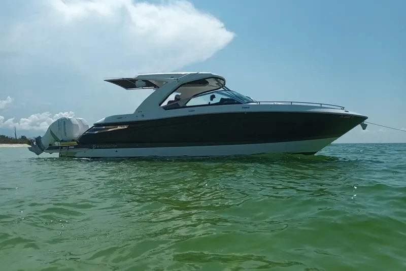 The Image of 2023 Four Winns H350 OB boat on calm water under clear sky. - 0