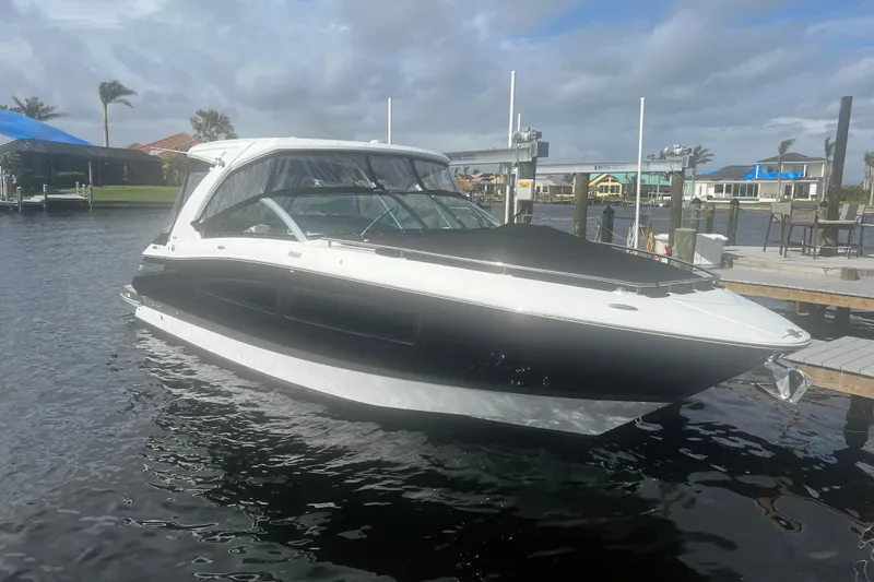 Slide: The Image of 2023 Four Winns H350 OB boat docked on a sunny day, showcasing sleek design. - 1
