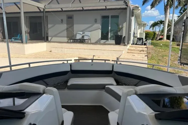 Slide: The Image of 2023 Four Winns H350 OB boat interior with seating, docked near a modern house. - 10