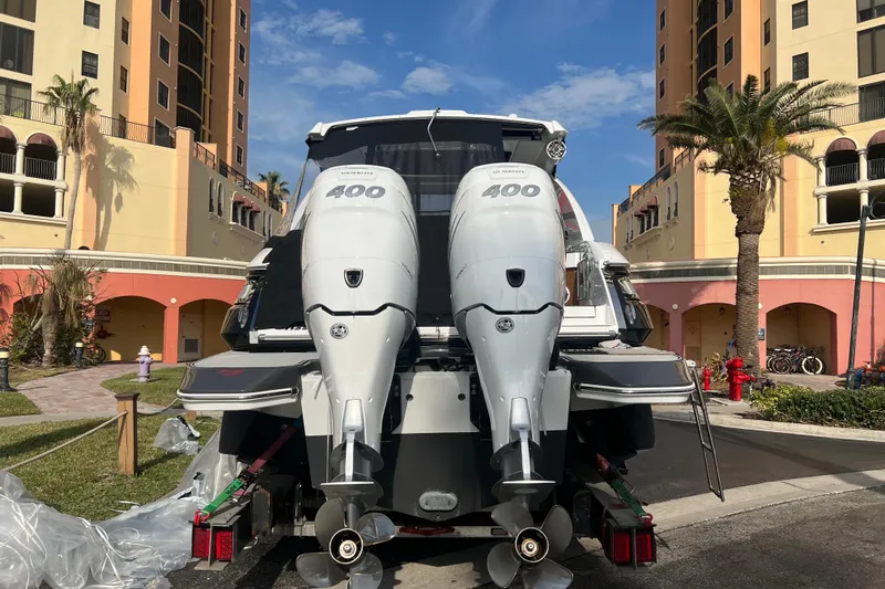 Slide: The Image of 2023 Four Winns H350 OB boat with dual 400 horsepower engines, parked near colorful buildings. - 2