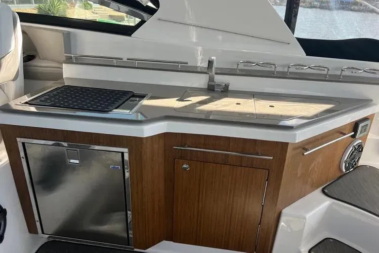 Slide: The Image of 2023 Four Winns H350 OB boat kitchenette with sink, grill, and storage. - 20