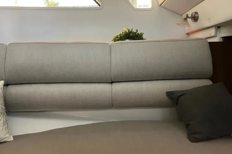 Slide: The Image of 2023 Four Winns H350 OB interior with gray cushioned seating and decorative pillows. - 24