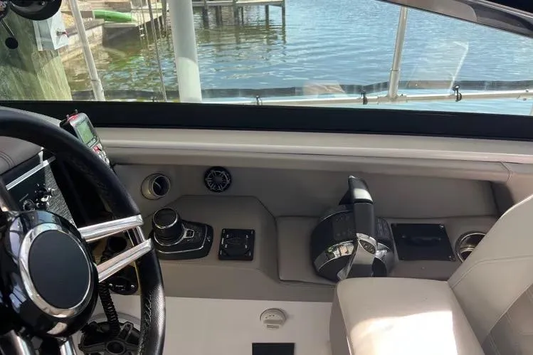 Slide: The Image of 2023 Four Winns H350 OB boat cockpit with steering wheel and controls, dockside view. - 29
