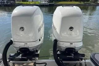 Slide: The Image of 2023 Four Winns H350 OB boat with twin outboard engines on a calm water backdrop. - 33
