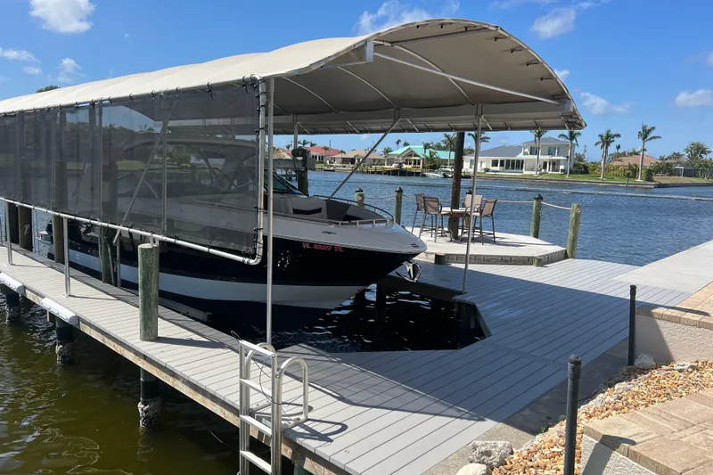 Slide: The Image of 2023 Four Winns H350 OB boat docked under canopy on sunny waterfront. - 5