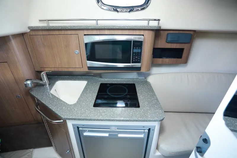 Slide: The Image of 2016 Boston Whaler 285 Conquest cabin kitchen with sink, microwave, and stove. - 13