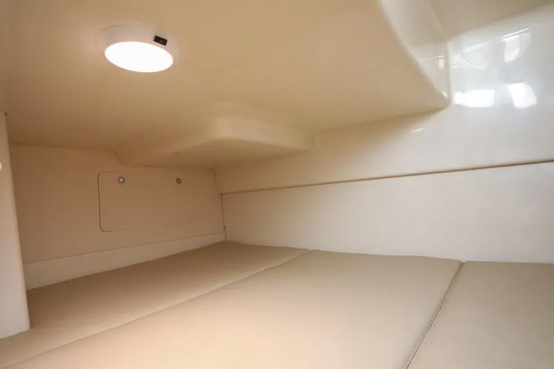 Slide: The Image of 2016 Boston Whaler 285 Conquest cabin interior with beige cushions and overhead light. - 16