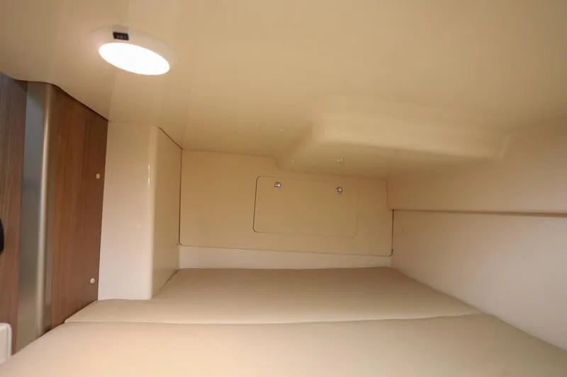 Slide: The Image of 2016 Boston Whaler 285 Conquest cabin interior with soft lighting and beige upholstery. - 17