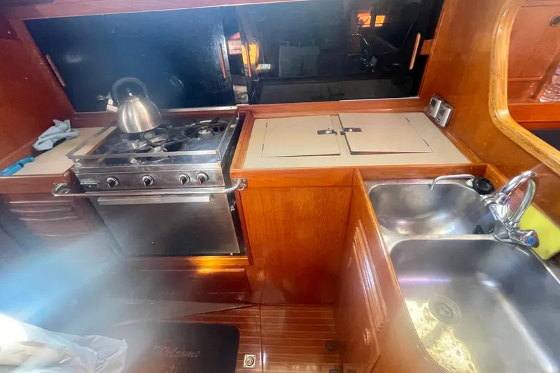 Slide: The Image of 1981 Nautor Swan cutter yacht kitchen with stove, sink, and wooden cabinetry. - 17