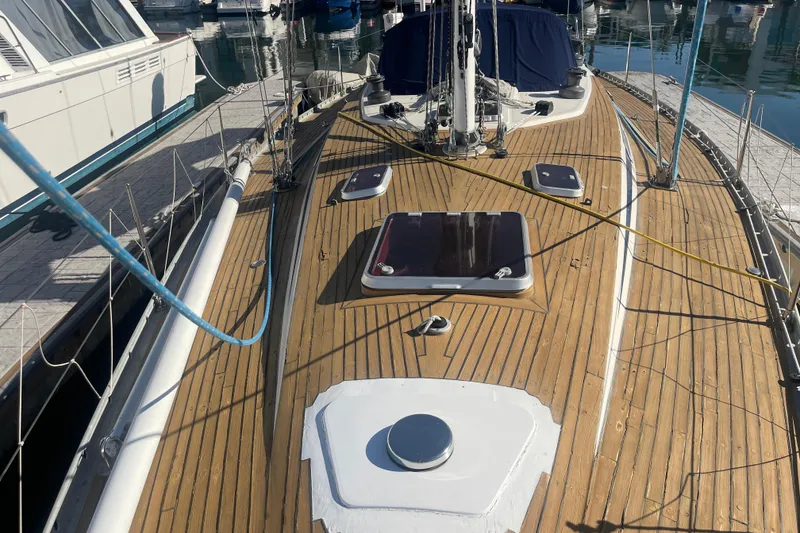 Slide: The Image of 1981 Nautor Swan cutter sailboat with wooden deck, docked in marina. - 6