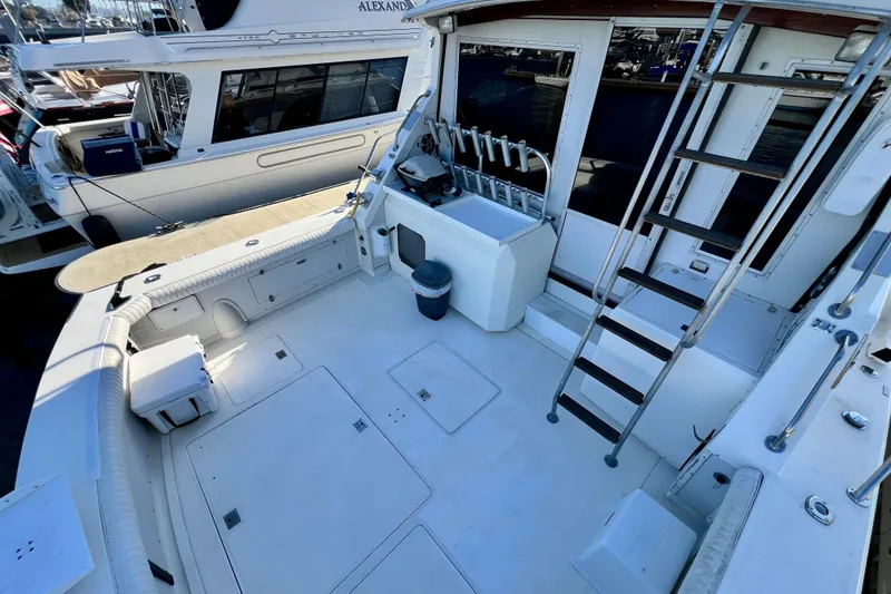 Slide: The Image of 1982 Bertram 46 Convertible yacht deck with seating, ladder, and fishing rod holders. - 28