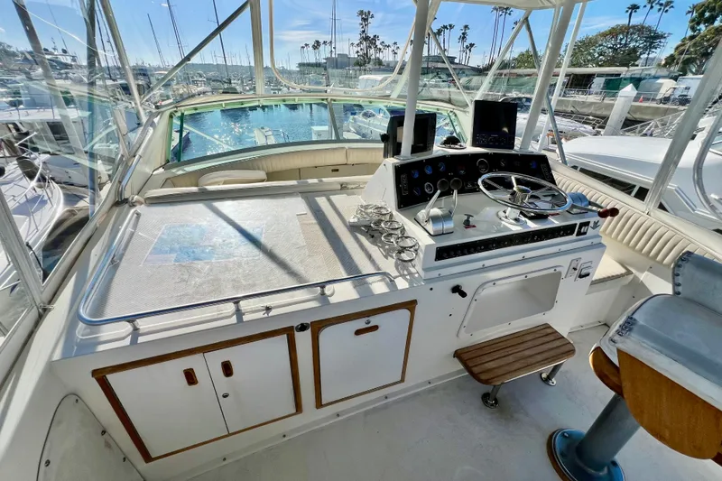 Slide: The Image of 1982 Bertram 46 Convertible yacht helm with steering wheel, controls, and marina view. - 39