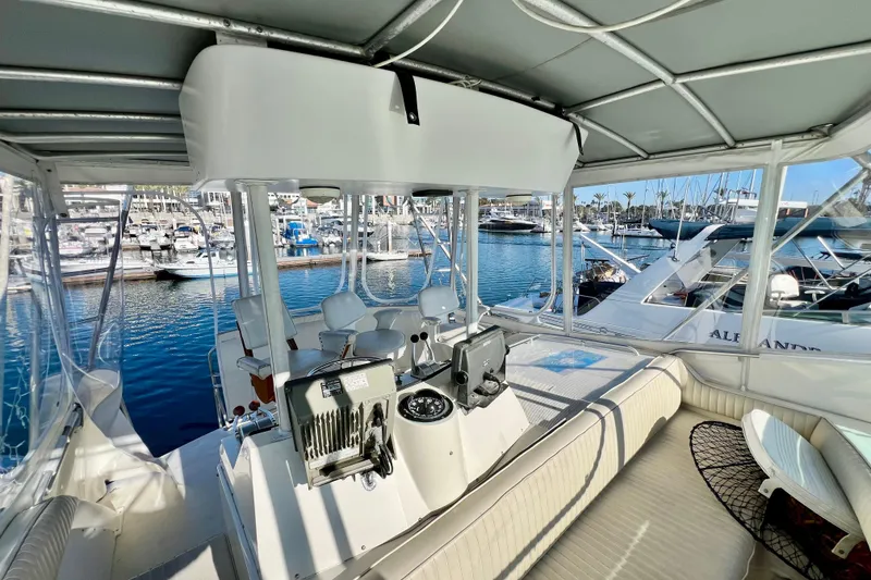 Slide: The Image of 1982 Bertram 46 Convertible yacht interior with marina view, featuring helm and seating area. - 46