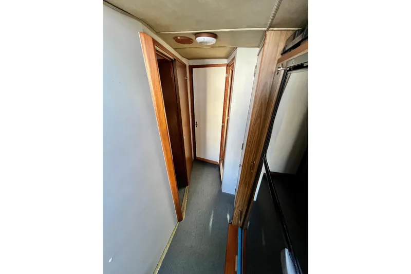 Slide: The Image of Narrow hallway inside 1982 Bertram 46 Convertible yacht with wooden doors and carpeted floor. - 65