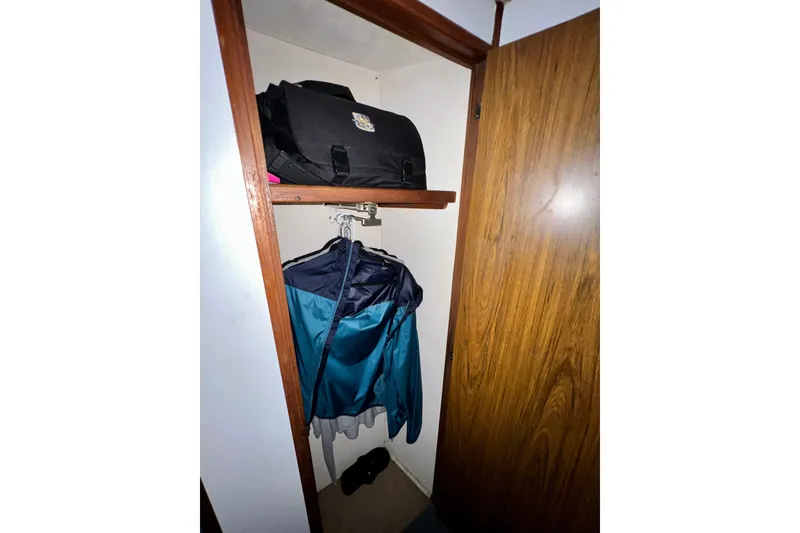 Slide: The Image of Closet interior on 1982 Bertram 46 Convertible with hanging clothes and a bag. - 73