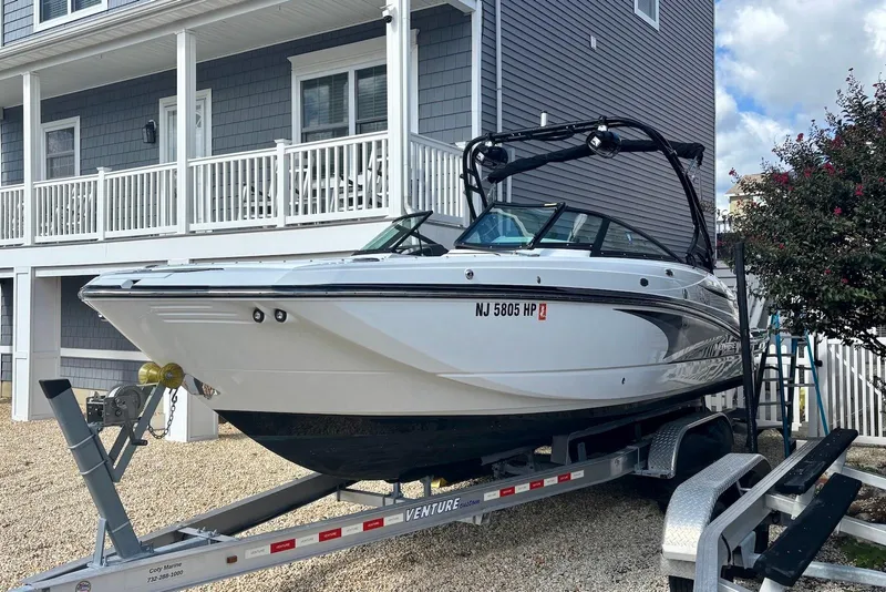 The Image of 2021 Monterey M-65 boat on trailer, parked near a house with gray siding. - 0