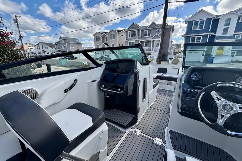 Slide: The Image of 2021 Monterey M-65 boat interior with modern dashboard and seating, parked near residential homes. - 13