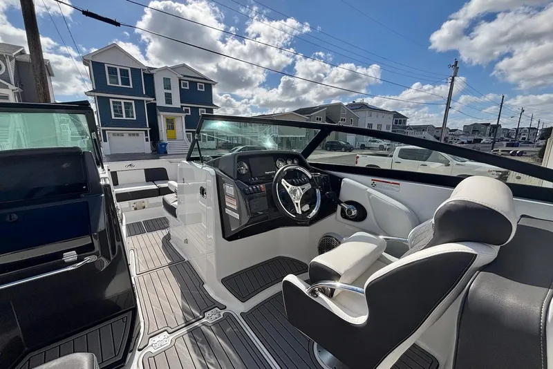 Slide: The Image of 2021 Monterey M-65 boat interior with modern dashboard and seating, under a partly cloudy sky. - 6