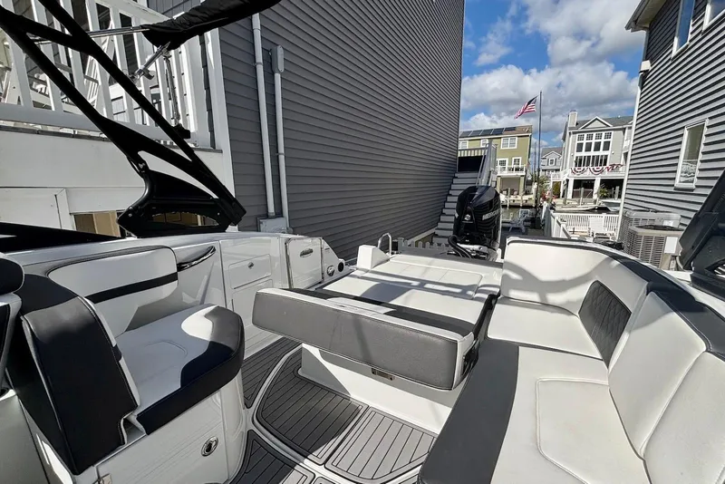 Slide: The Image of 2021 Monterey M-65 boat with sleek seating, docked between houses under a blue sky. - 9