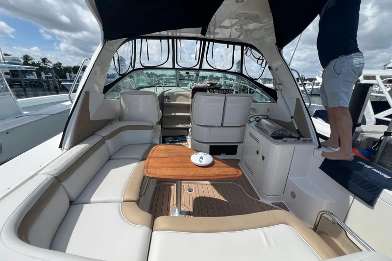 Slide: The Image of 2005 Sea Ray Sundancer 350 interior with seating, table, and helm, docked at marina. - 8
