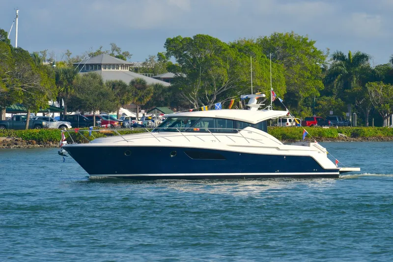 The Image of 2018 Tiara Yachts C44 Coupe cruising on a scenic waterway with lush greenery. - 0