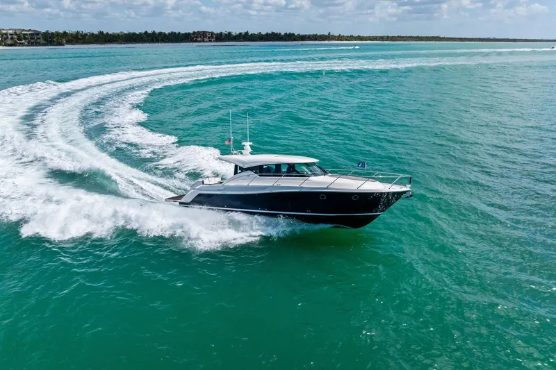 Slide: The Image of 2018 Tiara Yachts C44 Coupe cruising on turquoise waters, creating a dynamic wake. - 23