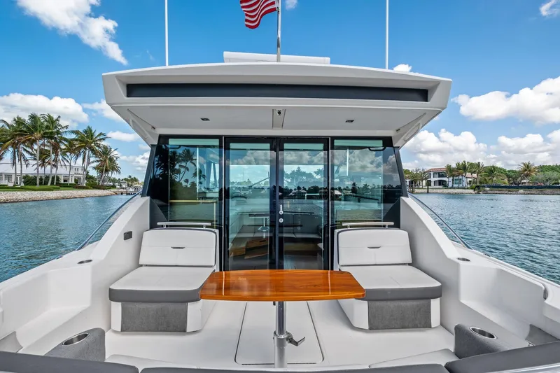Slide: The Image of 2018 Tiara Yachts C44 Coupe, luxury yacht with seating and table, docked by palm trees. - 34