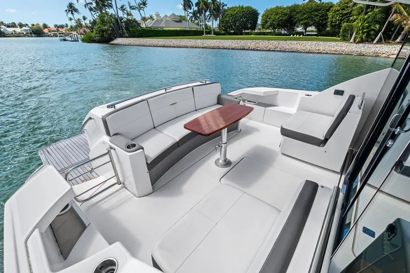 Slide: The Image of 2018 Tiara Yachts C44 Coupe, elegant deck with seating and table, scenic waterfront view. - 35