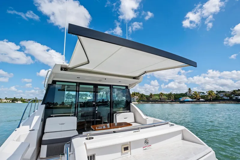 Slide: The Image of 2018 Tiara Yachts C44 Coupe on water, featuring spacious deck and retractable awning. - 38