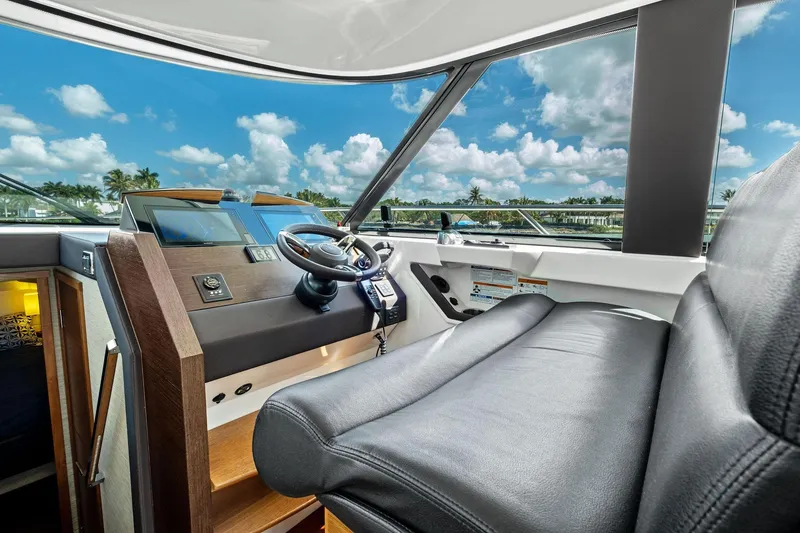 Slide: The Image of 2018 Tiara Yachts C44 Coupe helm with leather seating and modern controls, under a blue sky. - 49
