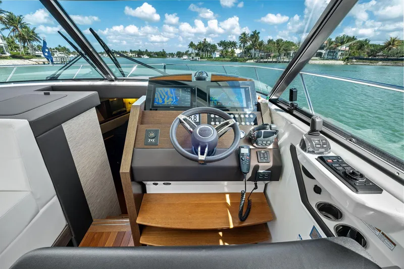 Slide: The Image of 2018 Tiara Yachts C44 Coupe helm with modern navigation equipment and scenic waterway view. - 50