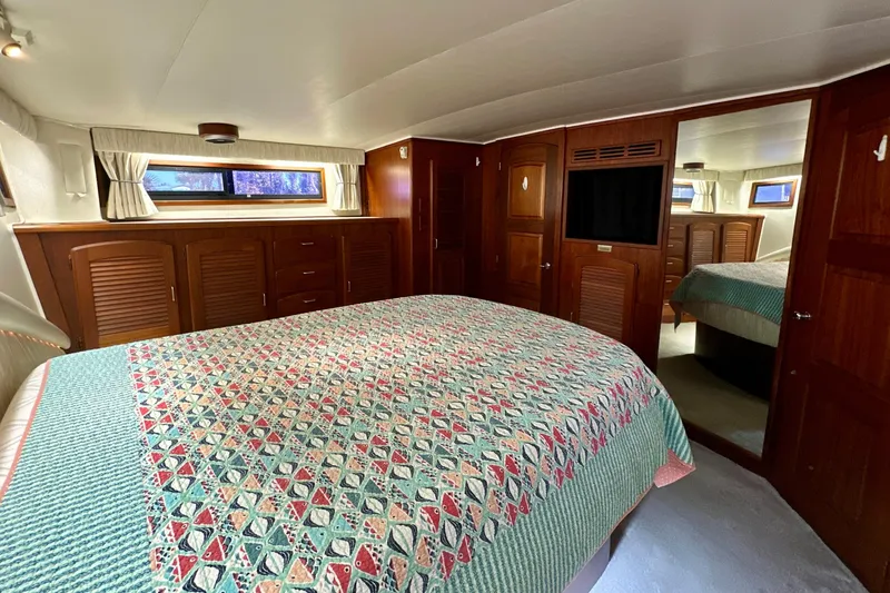 Slide: The Image of Luxurious bedroom interior of 1988 Californian 45 Motor Yacht with patterned bedding and wooden cabinetry. - 23