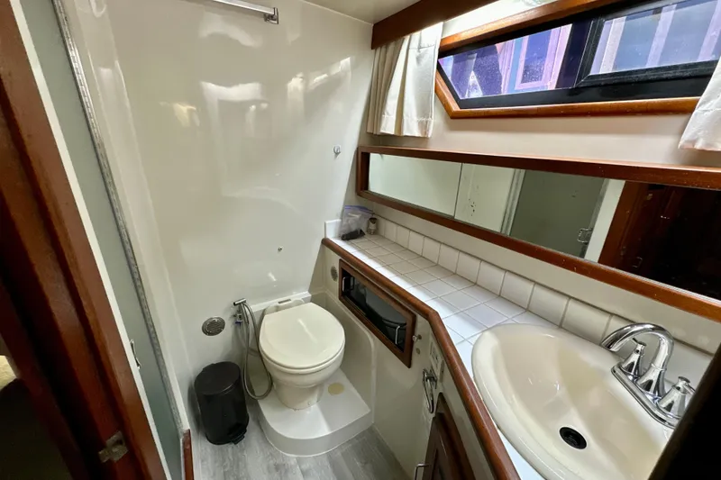 Slide: The Image of 1988 Californian 45 Motor Yacht bathroom with toilet, sink, mirror, and window. - 26
