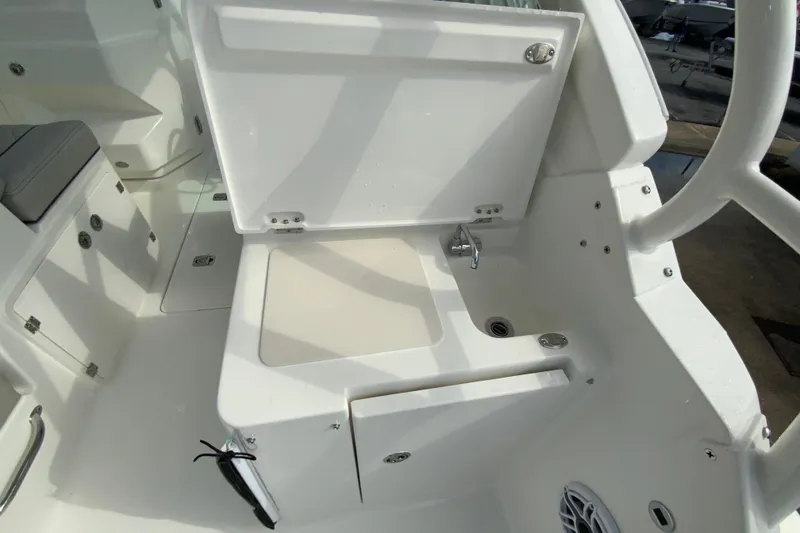 Slide: The Image of 2026 Pursuit DC 266 Dual Console boat interior with open storage compartment and sink. - 10