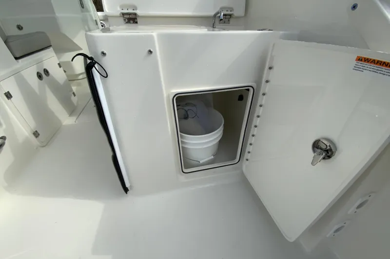 Slide: The Image of 2026 Pursuit DC 266 Dual Console boat interior storage compartment with bucket. - 11