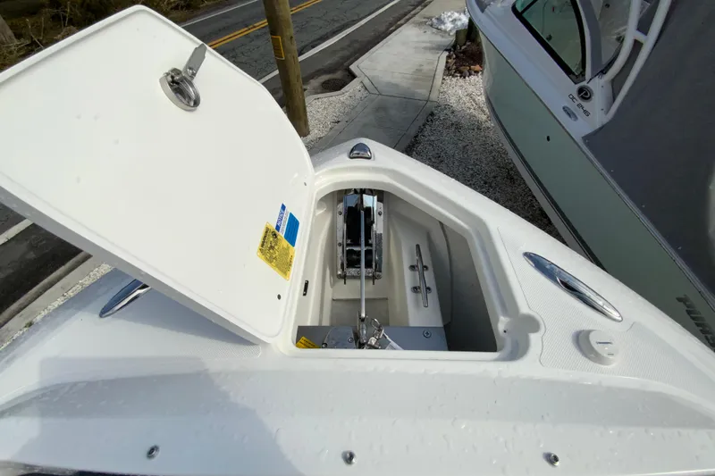 Slide: The Image of Open anchor compartment on 2026 Pursuit DC 266 Dual Console boat, docked near a road. - 13