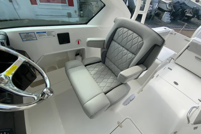 Slide: The Image of 2026 Pursuit DC 266 Dual Console boat interior with luxurious captain's seat and steering wheel. - 20
