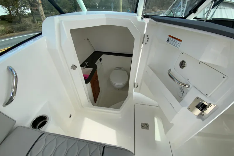 Slide: The Image of 2026 Pursuit DC 266 Dual Console boat interior with compact bathroom and sink. - 22