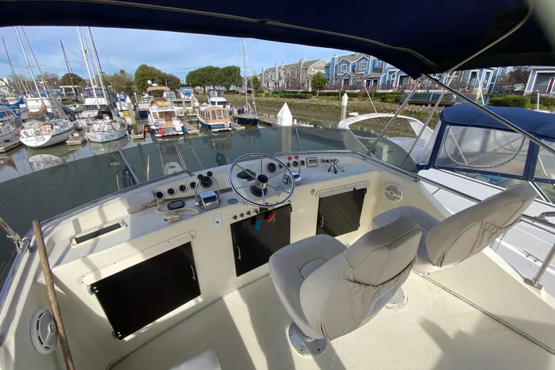 Slide: The Image of 1986 Tollycraft Flybridge Convertible boat interior with marina view, featuring helm and seating. - 19