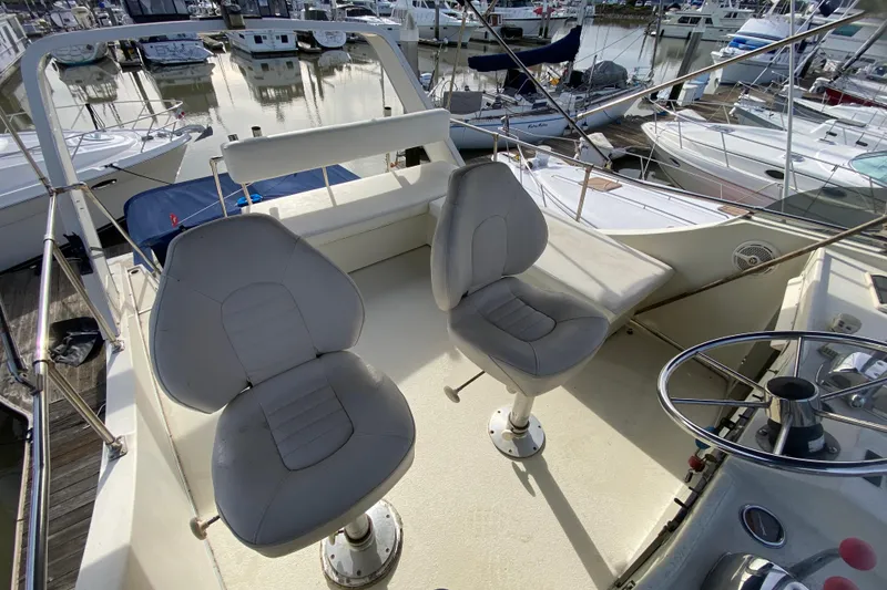 Slide: The Image of 1986 Tollycraft Flybridge Convertible with dual seats and steering wheel, docked at marina. - 20
