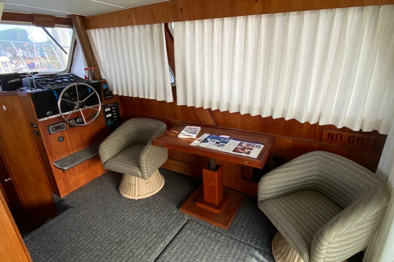 Slide: The Image of 1986 Tollycraft Flybridge Convertible interior with helm, chairs, and table. - 7